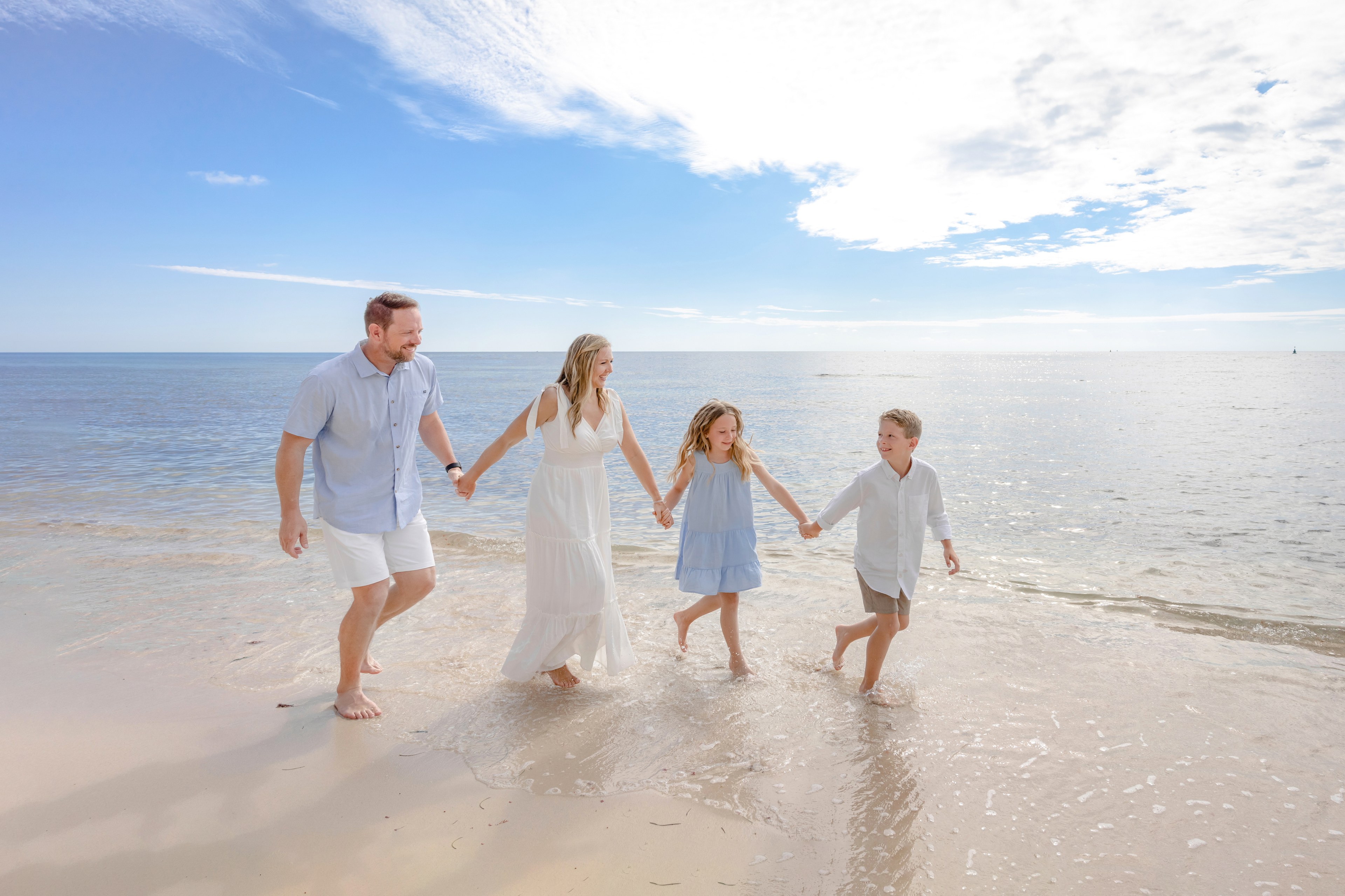 IVAE Studios golden-hour beach portrait of parents holding their baby on a calm Riviera Maya shoreline near Cancun, Mexico, on the family's first trip abroad