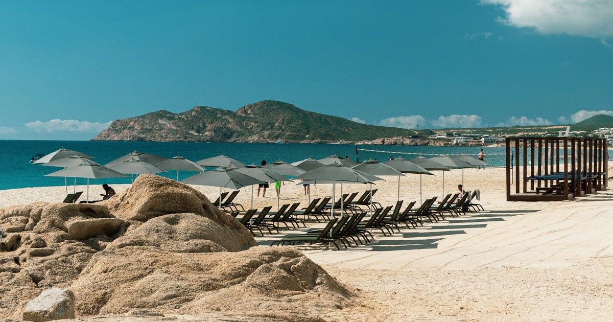 Medano Beach golden shoreline lined with luxury resorts in Cabo San Lucas Bay