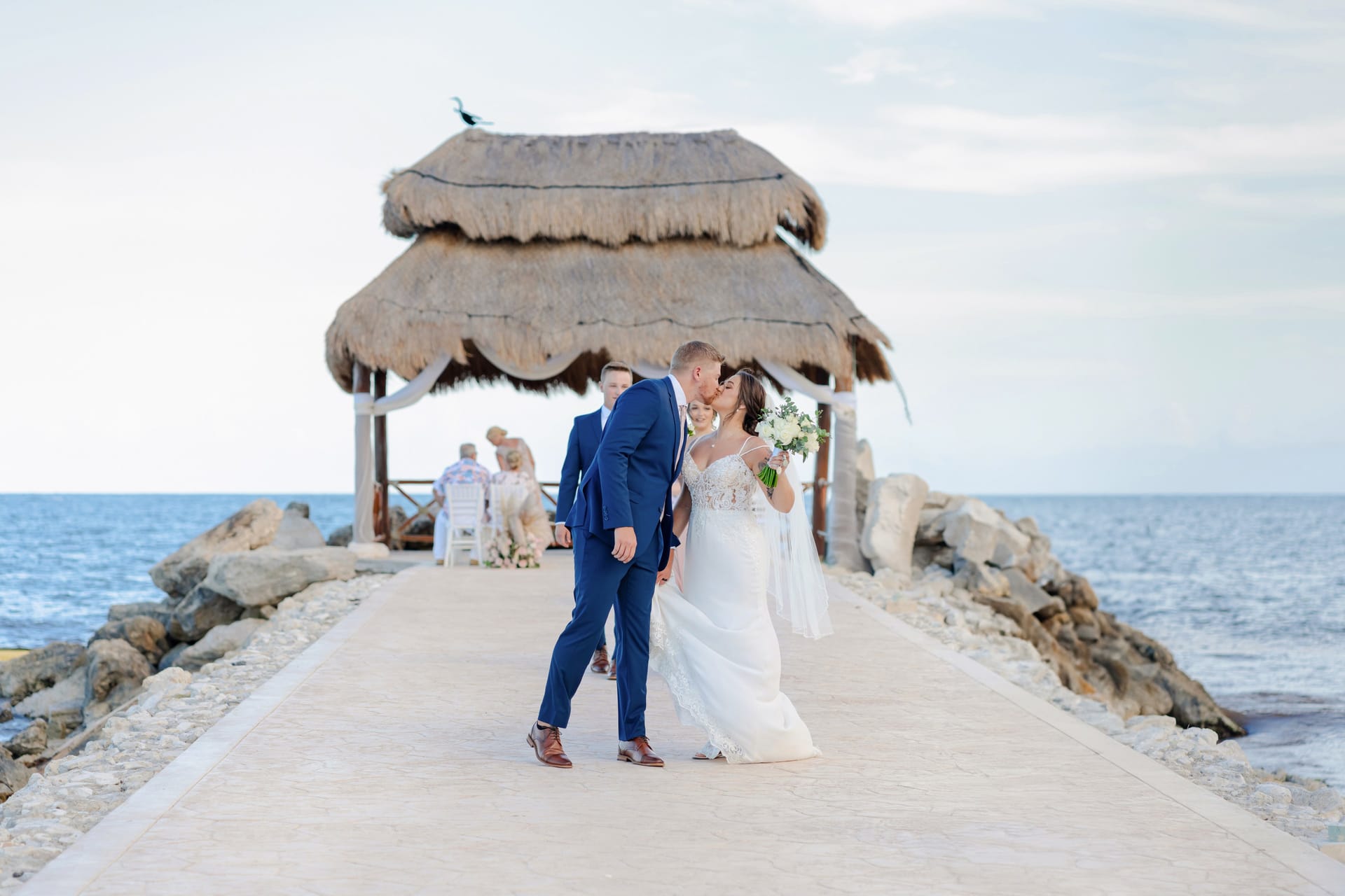 Bride and groom kissing on an ocean pier at a Cancún Hotel Zone resort, photographed by IVAE Studios