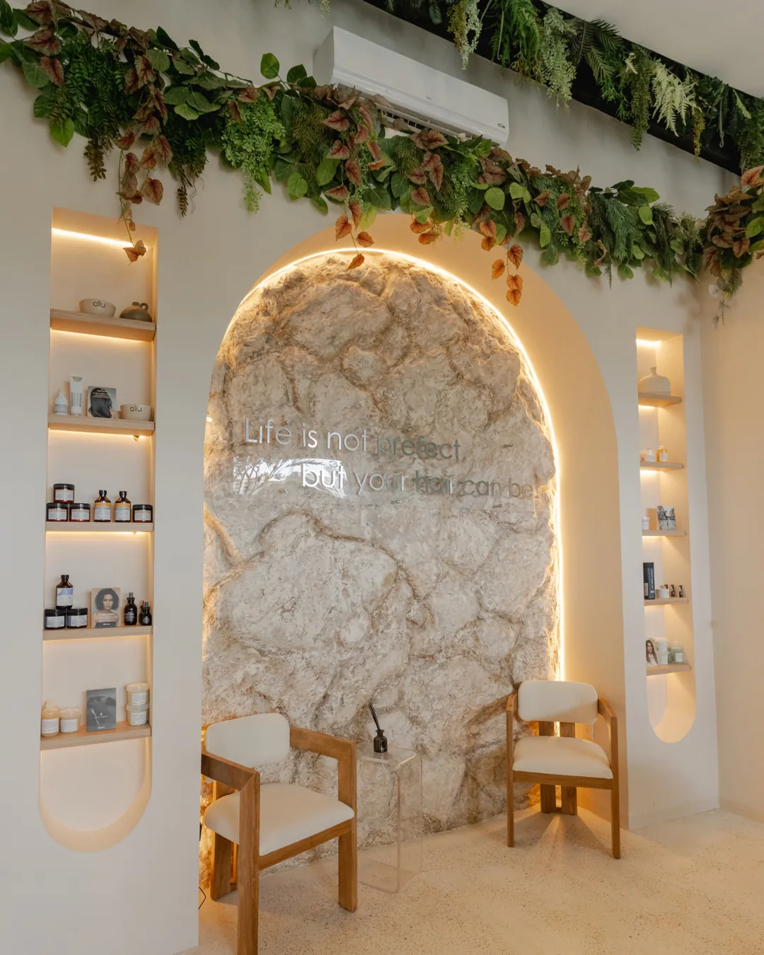 Oliu Hair salon in Cancun with a lit stone arch and product shelves, photographed by IVAE