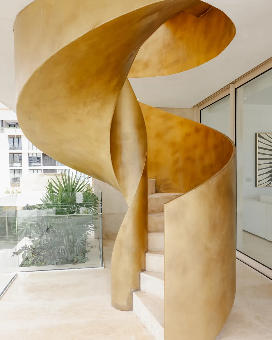Golden spiral staircase in a residential project in Cancun, photographed by IVAE